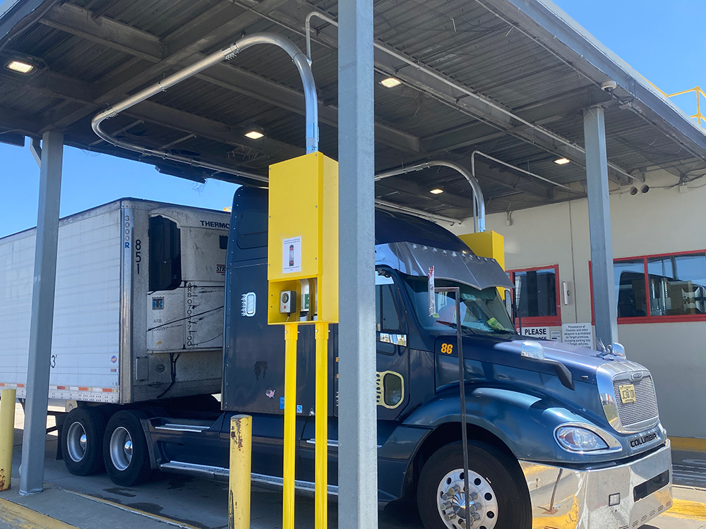 An 18-wheeler truck stops at the pnuematic tube station in the drive-thru at a distribution center.