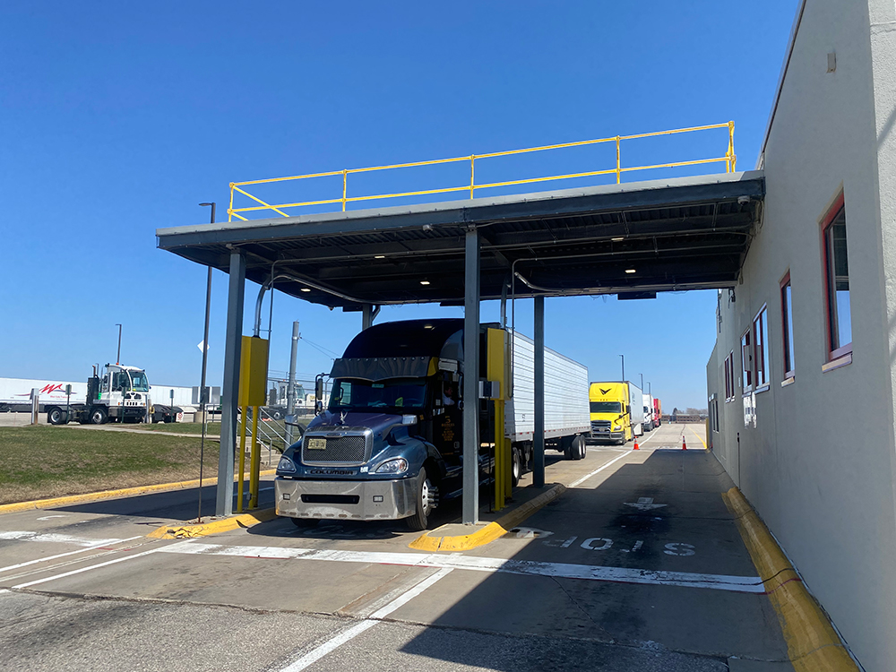18-wheeler trucks drive through drive-up station at a distribution center.